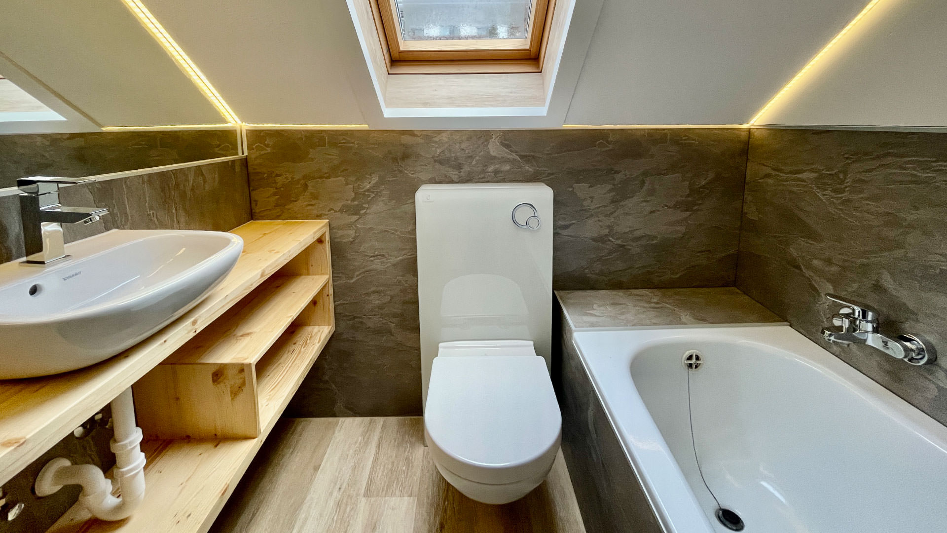 Badezimmer mit Toilette, Waschbecken und Badewanne nach der Renovierung